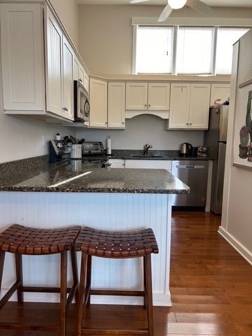 45 Main Street, Unit 221 Wareham, MA 02571 - Photo 19 of 36 a kitchen with stainless steel appliances granite countertop a stove a sink dishwasher a microwave oven and a refrigerator with wooden floor