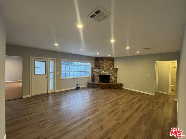 an empty room with wooden floor and fireplace