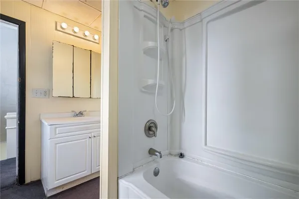 a bathroom with a tub sink and mirror