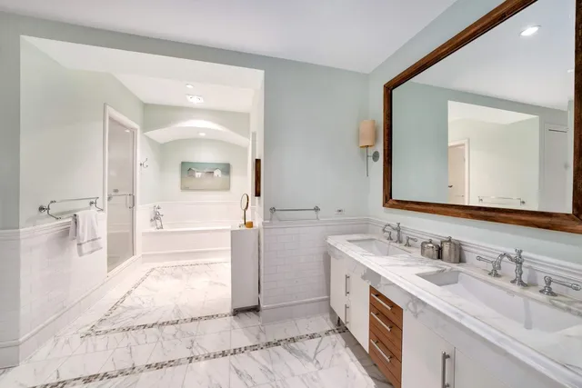 a spacious bathroom with a tub sink double vanity and a mirror