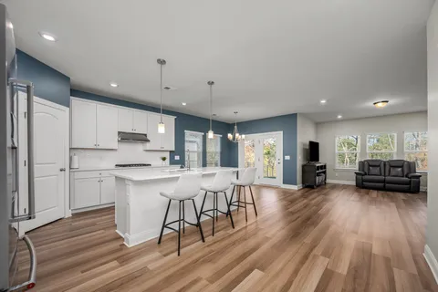 a kitchen with stainless steel appliances a dining table chairs stove refrigerator and cabinets