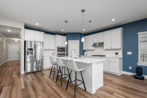 a kitchen with stainless steel appliances a refrigerator a stove top oven and a center island with wooden floor