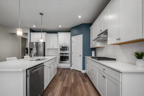 a kitchen with stainless steel appliances kitchen island granite countertop a sink a stove and refrigerator