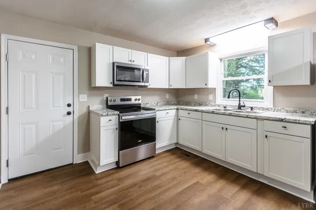 a kitchen with granite countertop white cabinets a sink a window and stainless steel appliances