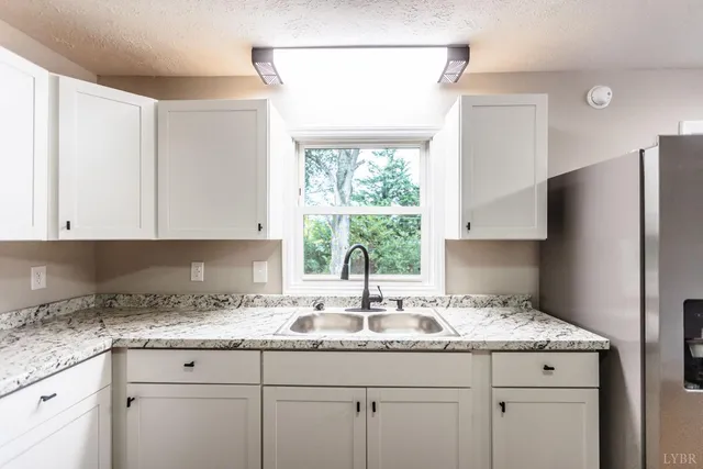 a kitchen with granite countertop white cabinets and a window