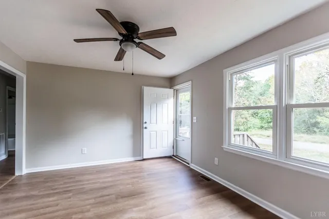 a view of an empty room with wooden floor and a window