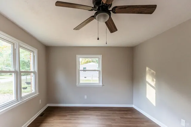 a view of an empty room with wooden floor and window
