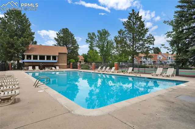 a view of swimming pool with outdoor seating and trees in the background