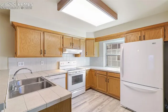 a kitchen with a refrigerator sink and white cabinets