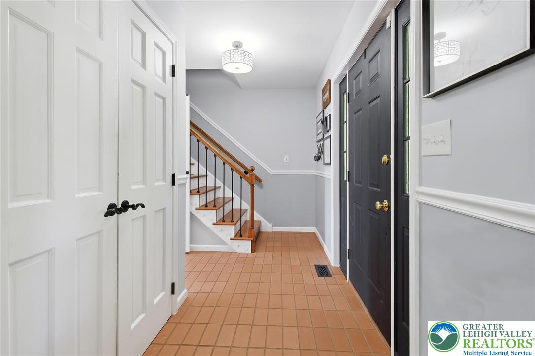 890 Lahr Road Nazareth, PA 18064 - Photo 5 of 71 A welcoming entry features durable tile flooring, leading to a staircase with a warm wood handrail.