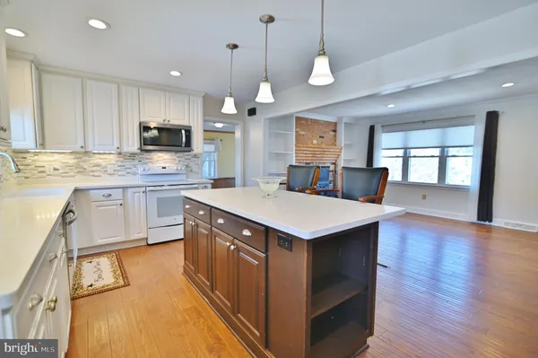 a kitchen with kitchen island granite countertop wooden floors and white cabinets