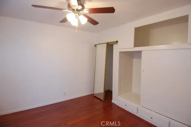 an empty room with closet and a ceiling fan