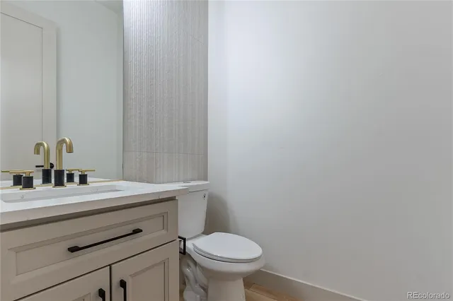a bathroom with a granite countertop toilet and a sink