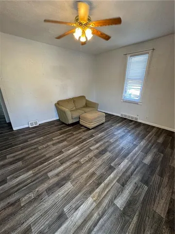 a view of a room with wooden floor and a ceiling fan