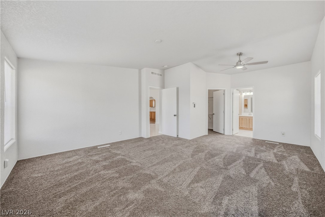 1890 West Dyer Road Pahrump, NV 89048 - Photo 8 of 40 This expansive primary bedroom offers ample space and plush carpeting, with convenient access to a private bath.