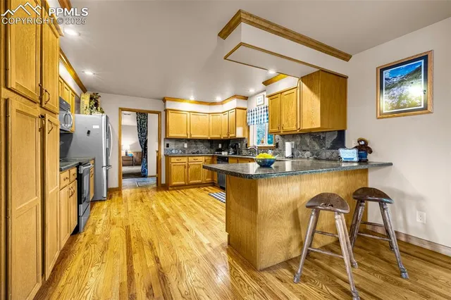 a kitchen with stainless steel appliances granite countertop a refrigerator a stove and a wooden floors