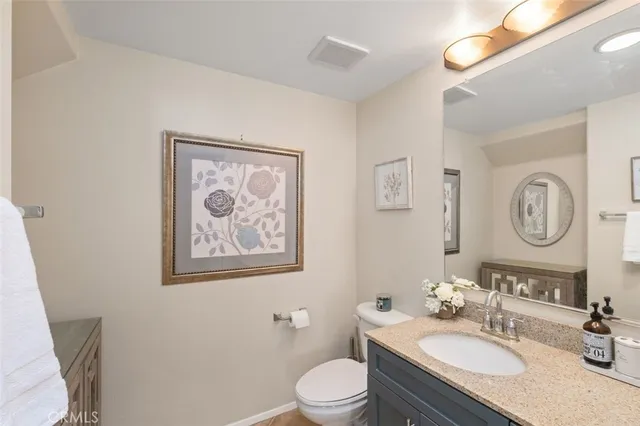 a bathroom with a granite countertop toilet a sink and a mirror