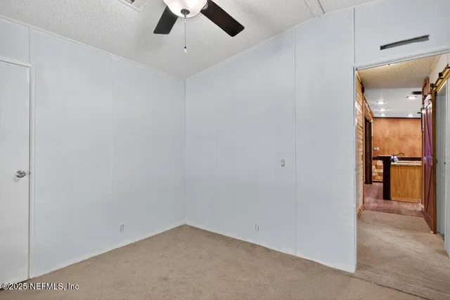an empty room with a ceiling fan and window