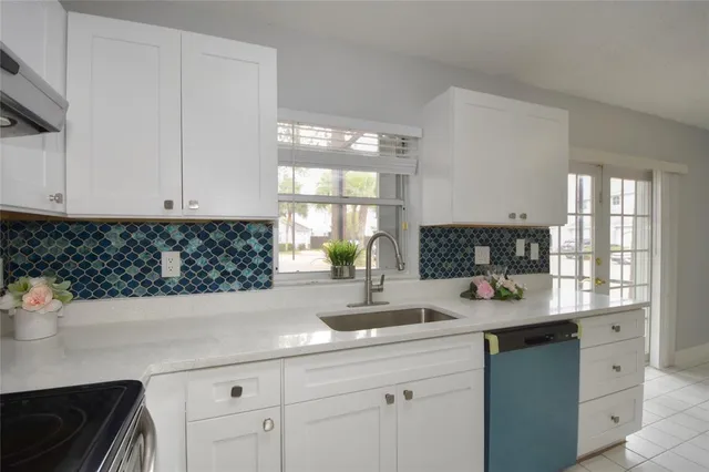 a kitchen with white cabinets a sink a window and appliances