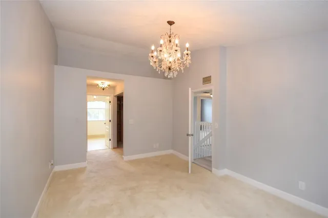 a view of an empty room with chandelier fan