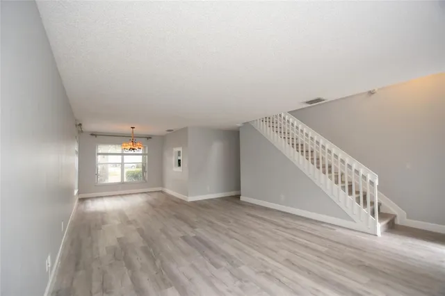 a view of an empty room with wooden floor and stairs