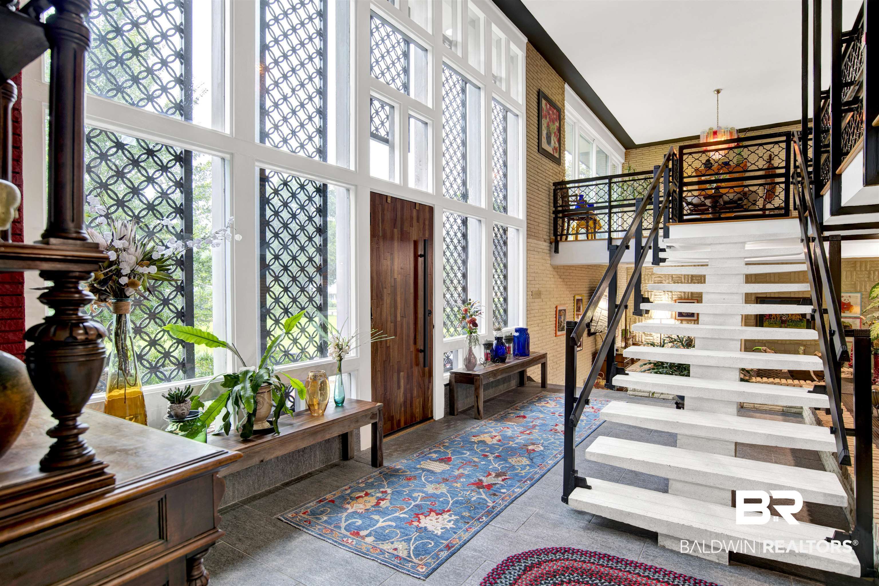809 Bernard Circle Mobile, AL 36693 - Photo 18 of 75 Two-story entry featuring expansive windows with decorative screens, a solid wood entry door, an open-tread staircase with black iron railings, and a second-story landing with coordinating iron balustrades