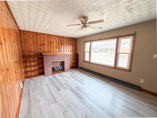 a view of an empty room with a window and wooden floor