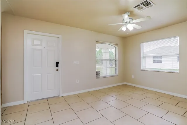 a view of an empty room with window and chandelier fan