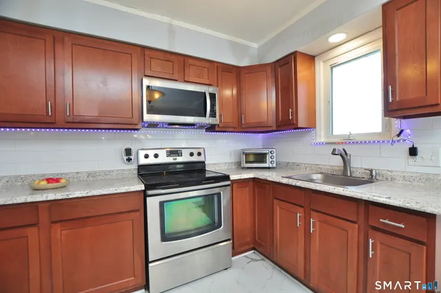 a kitchen with stainless steel appliances granite countertop wooden cabinets sink and a granite counter top