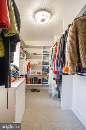 a view of walk in closet with clothes and shoes