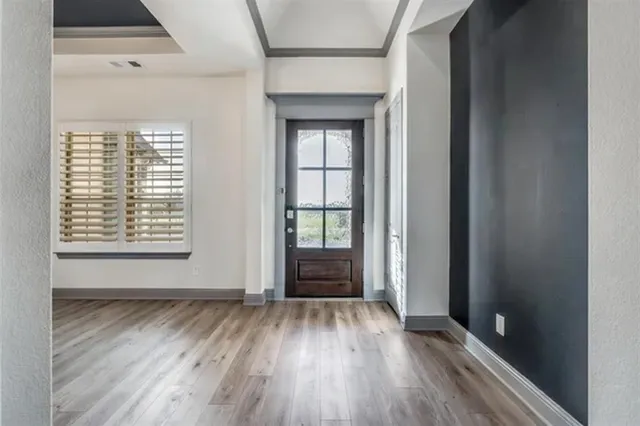 a view of an empty room with wooden floor and a window
