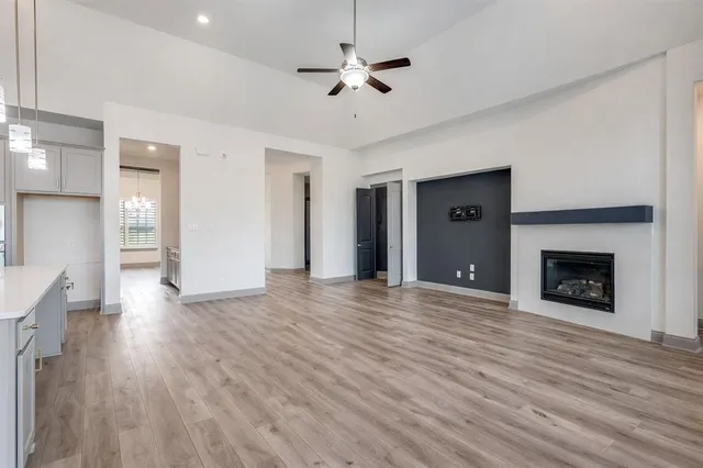 a view of a kitchen with kitchen island stainless steel appliances cabinets a sink and a wooden floor
