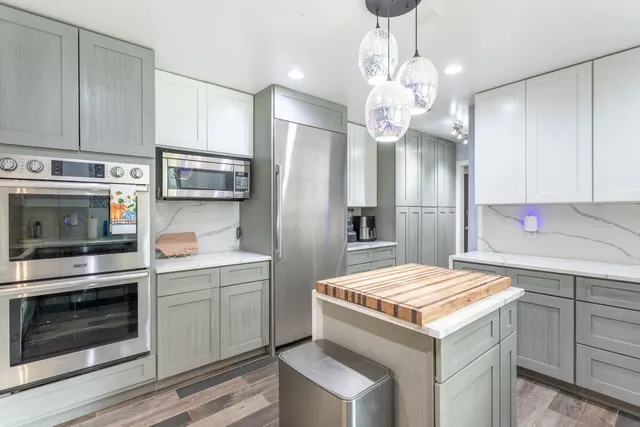 a dining hall with stainless steel appliances granite countertop a dining table chairs refrigerator and sink