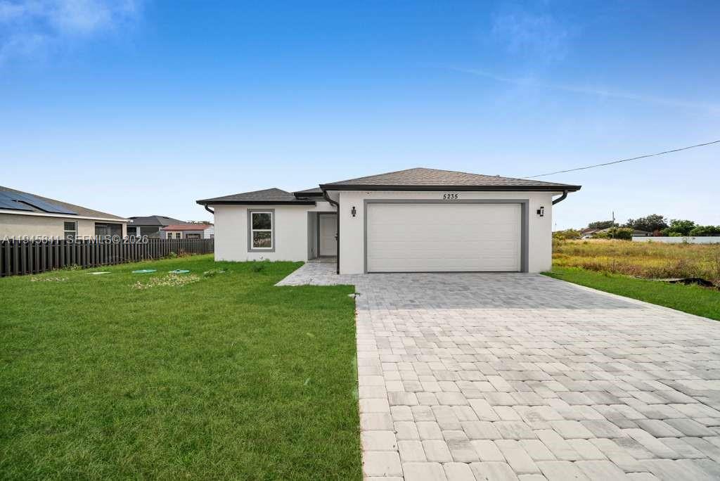 3210 10th Street Southwest, Unit 3210 Lehigh Acres, FL 33976 - Photo 1 of 29 a front view of a house with a yard and garage