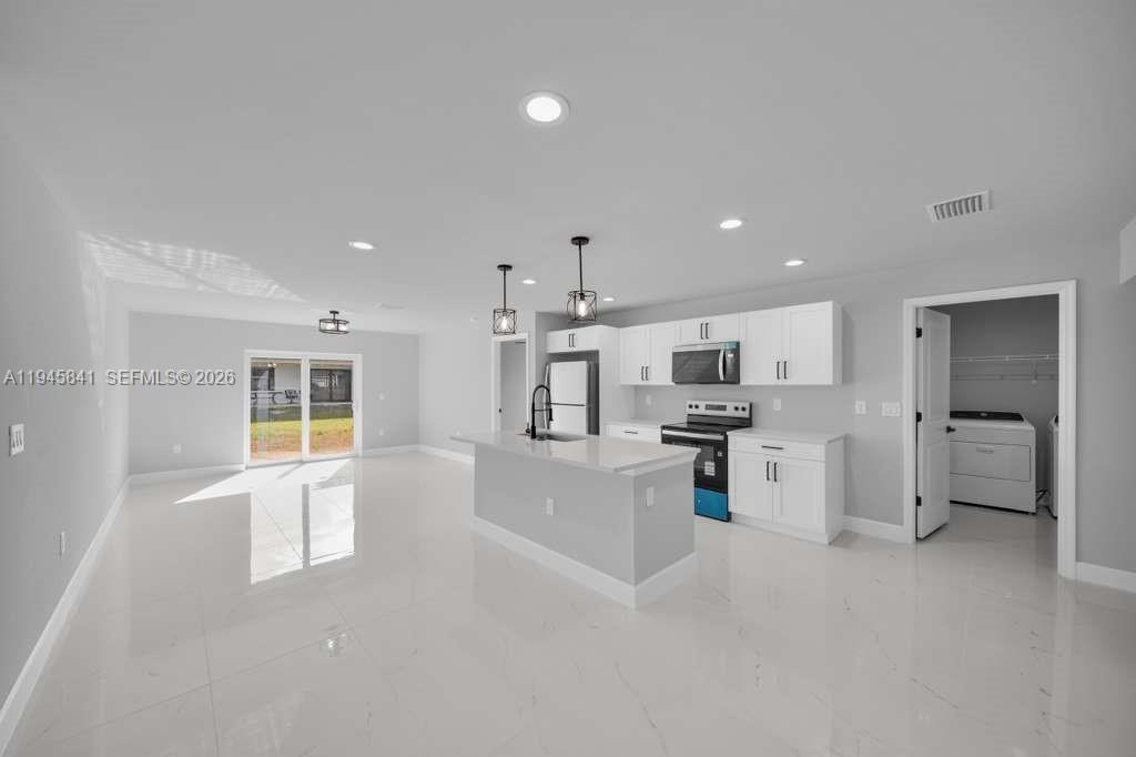 3210 10th Street Southwest, Unit 3210 Lehigh Acres, FL 33976 - Photo 12 of 29 a large kitchen with a large counter top stainless steel appliances and cabinets