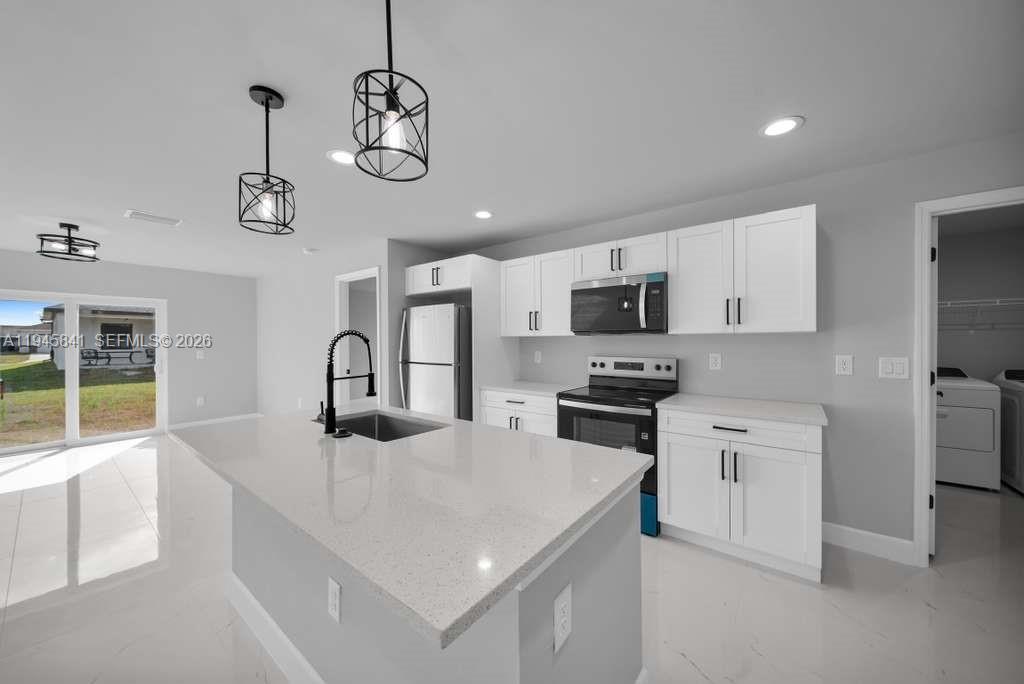 3210 10th Street Southwest, Unit 3210 Lehigh Acres, FL 33976 - Photo 14 of 29 a kitchen with stainless steel appliances kitchen island granite countertop a sink and microwave