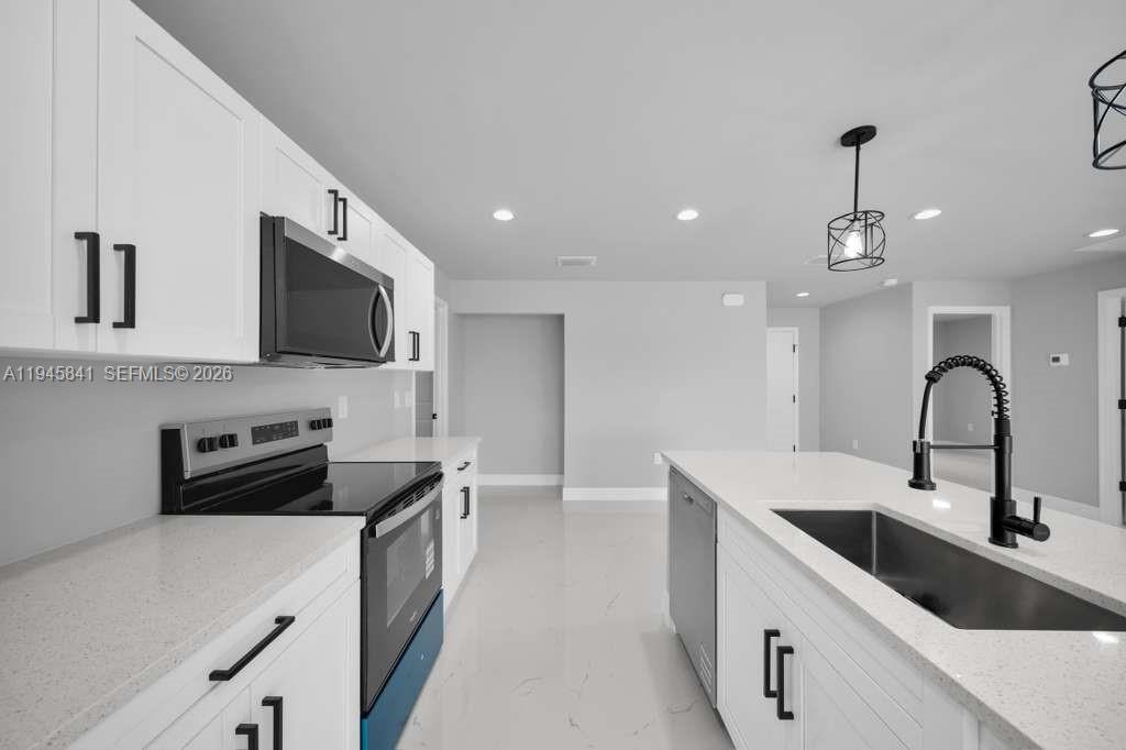3210 10th Street Southwest, Unit 3210 Lehigh Acres, FL 33976 - Photo 15 of 29 a kitchen with a sink stainless steel appliances and cabinets