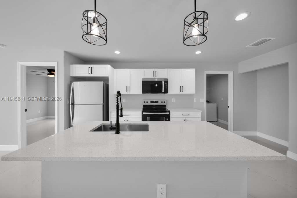 3210 10th Street Southwest, Unit 3210 Lehigh Acres, FL 33976 - Photo 16 of 29 a kitchen with a refrigerator a microwave and cabinets