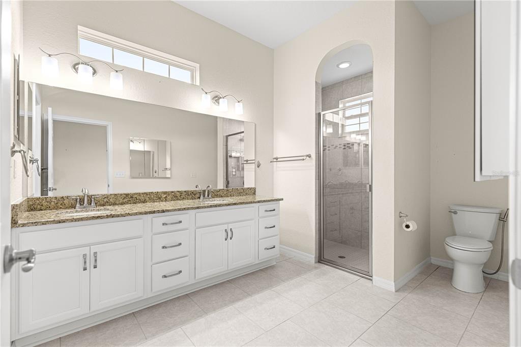 17306 Southeast 112th Court Road Summerfield, FL 34491 - Photo 22 of 42 a bathroom with a granite countertop sink a toilet and a mirror