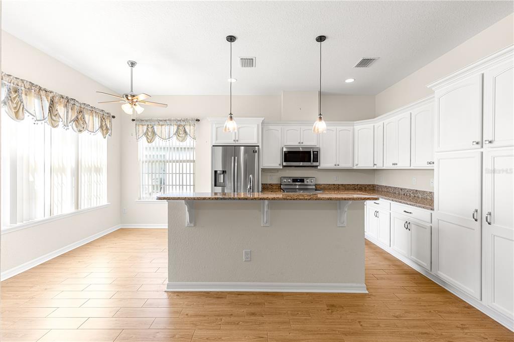 17306 Southeast 112th Court Road Summerfield, FL 34491 - Photo 7 of 42 a kitchen with stainless steel appliances kitchen island granite countertop a stove a sink and white cabinets with wooden floor