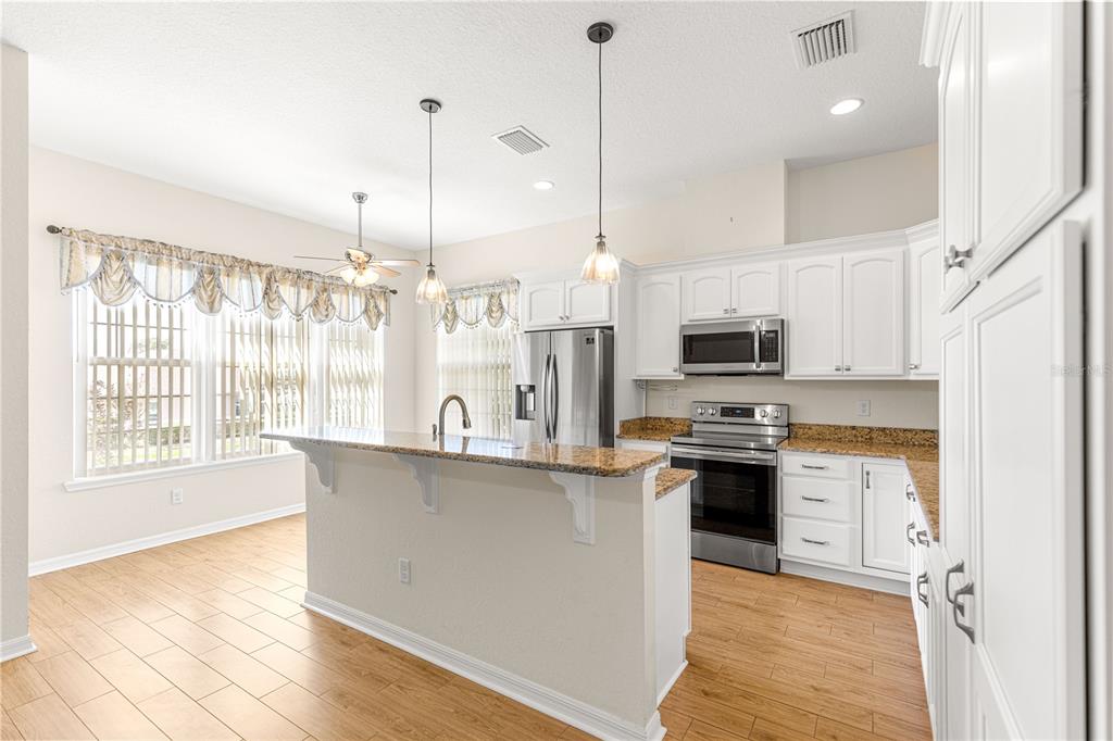 17306 Southeast 112th Court Road Summerfield, FL 34491 - Photo 8 of 42 a kitchen with stainless steel appliances a stove a sink a refrigerator a center island and wooden floor