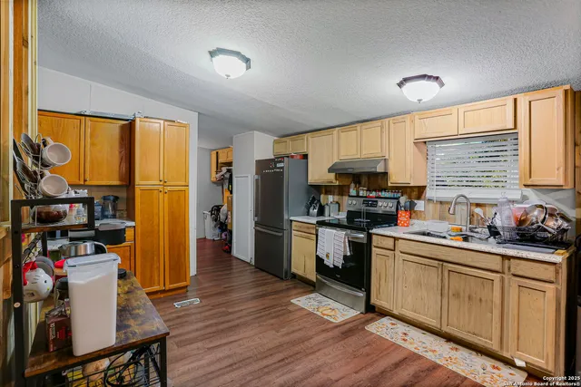 a kitchen with granite countertop a refrigerator stove top oven and sink