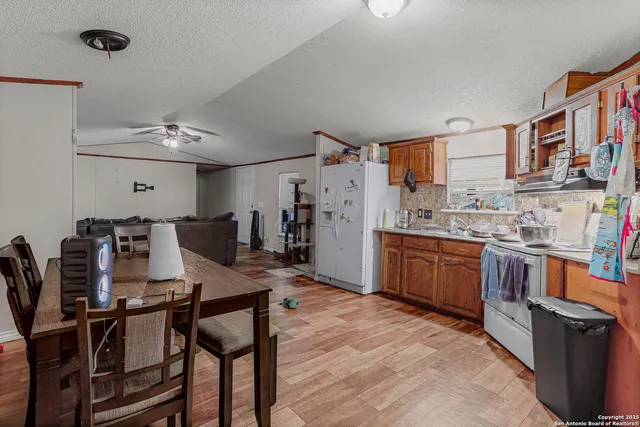 a kitchen with stainless steel appliances kitchen island granite countertop a table chairs in it and a refrigerator