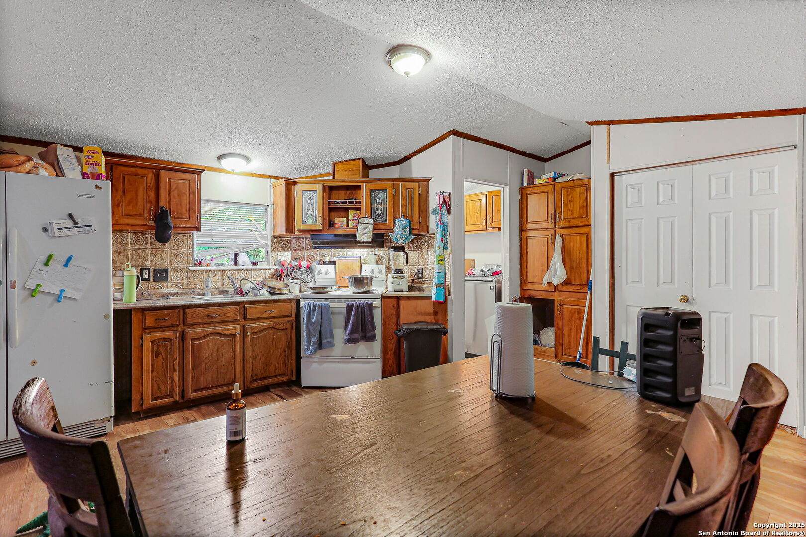 12925 Luckey Road Atascosa, TX 78002 - Photo 30 of 50 a kitchen with stainless steel appliances kitchen island granite countertop a refrigerator a stove a sink a dining table and chairs with wooden floor