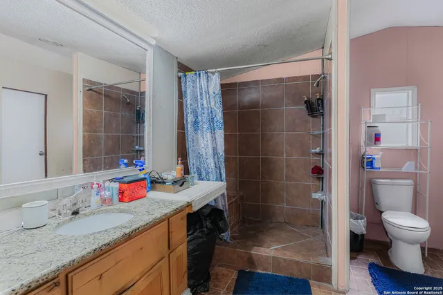 a bathroom with a granite countertop sink a toilet a mirror and shower