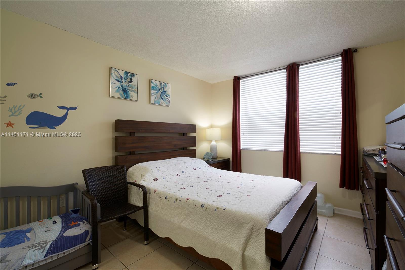 6705 Northwest 169th Street, Unit C205 Hialeah, FL 33015 - Photo 11 of 13 a bedroom with a bed and a table in it