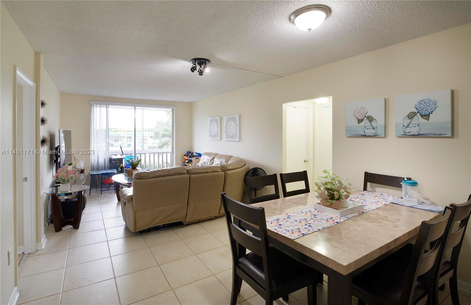 6705 Northwest 169th Street, Unit C205 Hialeah, FL 33015 - Photo 2 of 13 a living room with furniture a window and a dining table