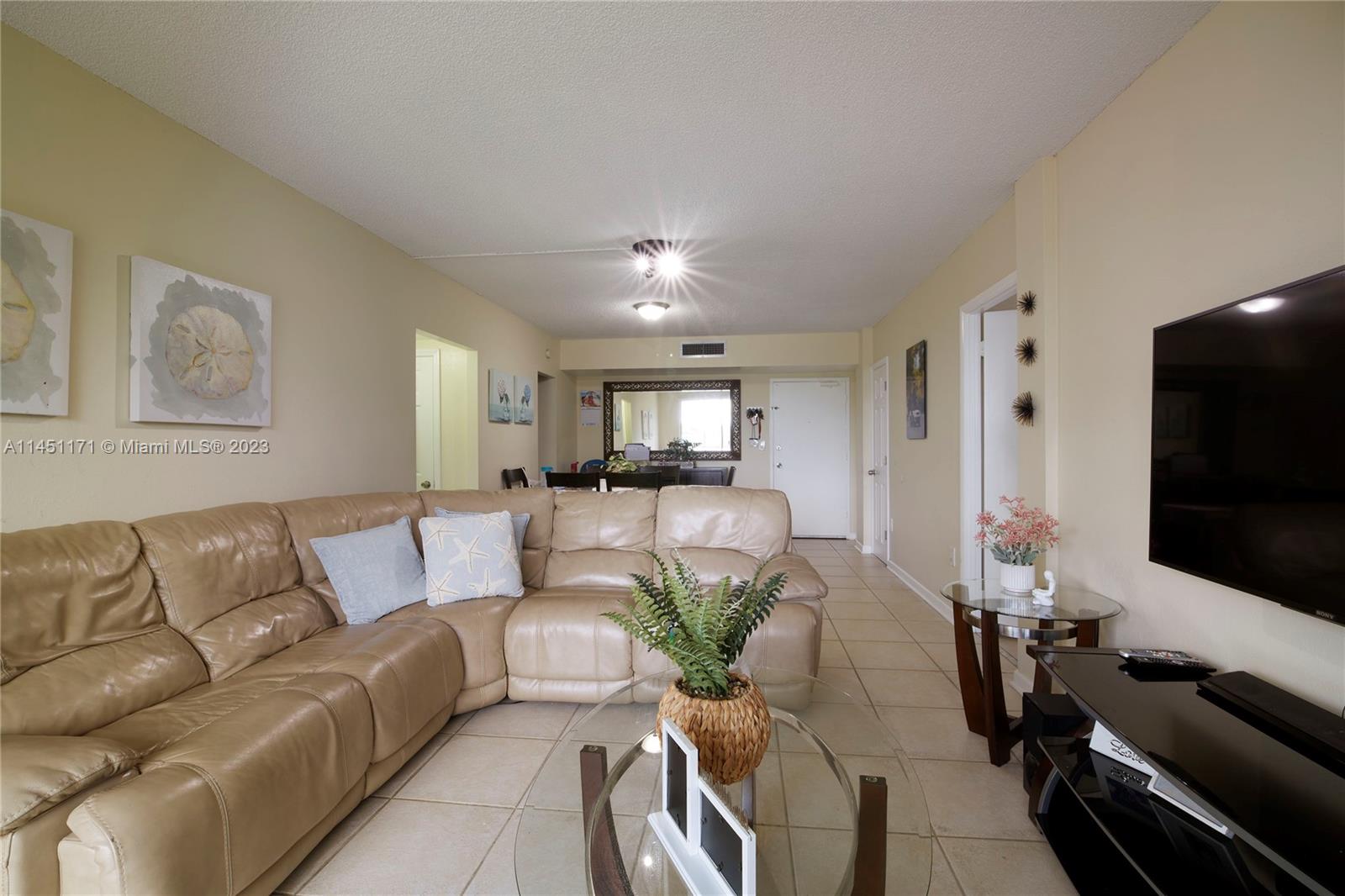 6705 Northwest 169th Street, Unit C205 Hialeah, FL 33015 - Photo 3 of 13 a living room with furniture and a flat screen tv