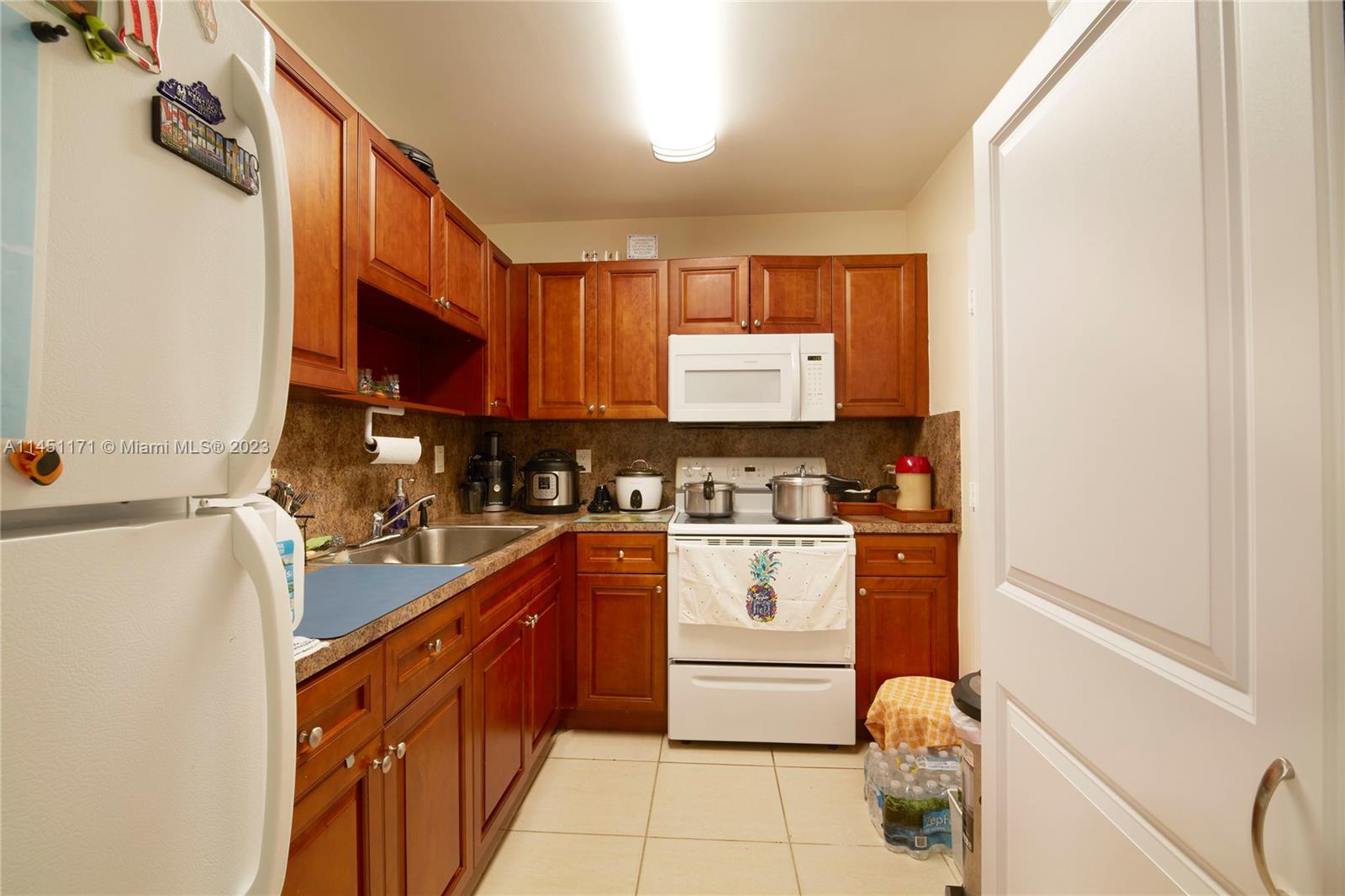 6705 Northwest 169th Street, Unit C205 Hialeah, FL 33015 - Photo 4 of 13 a kitchen with stainless steel appliances granite countertop a stove a sink and a refrigerator