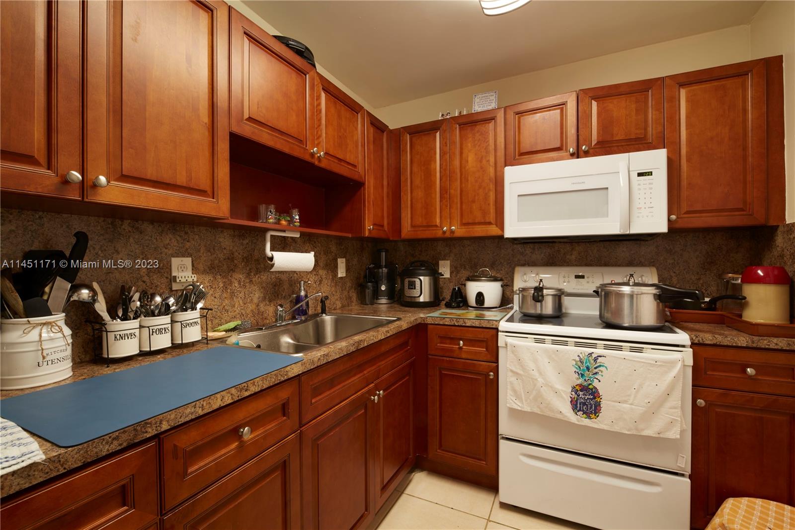 6705 Northwest 169th Street, Unit C205 Hialeah, FL 33015 - Photo 5 of 13 a kitchen with granite countertop cabinets stainless steel appliances and sink